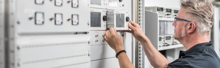 Technician inserts an SUMMIT 8800 flow computer inside a cabinet