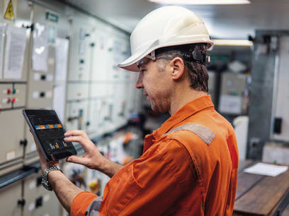 Technician in a control room on a ship looking on an ipad with ecomate screen