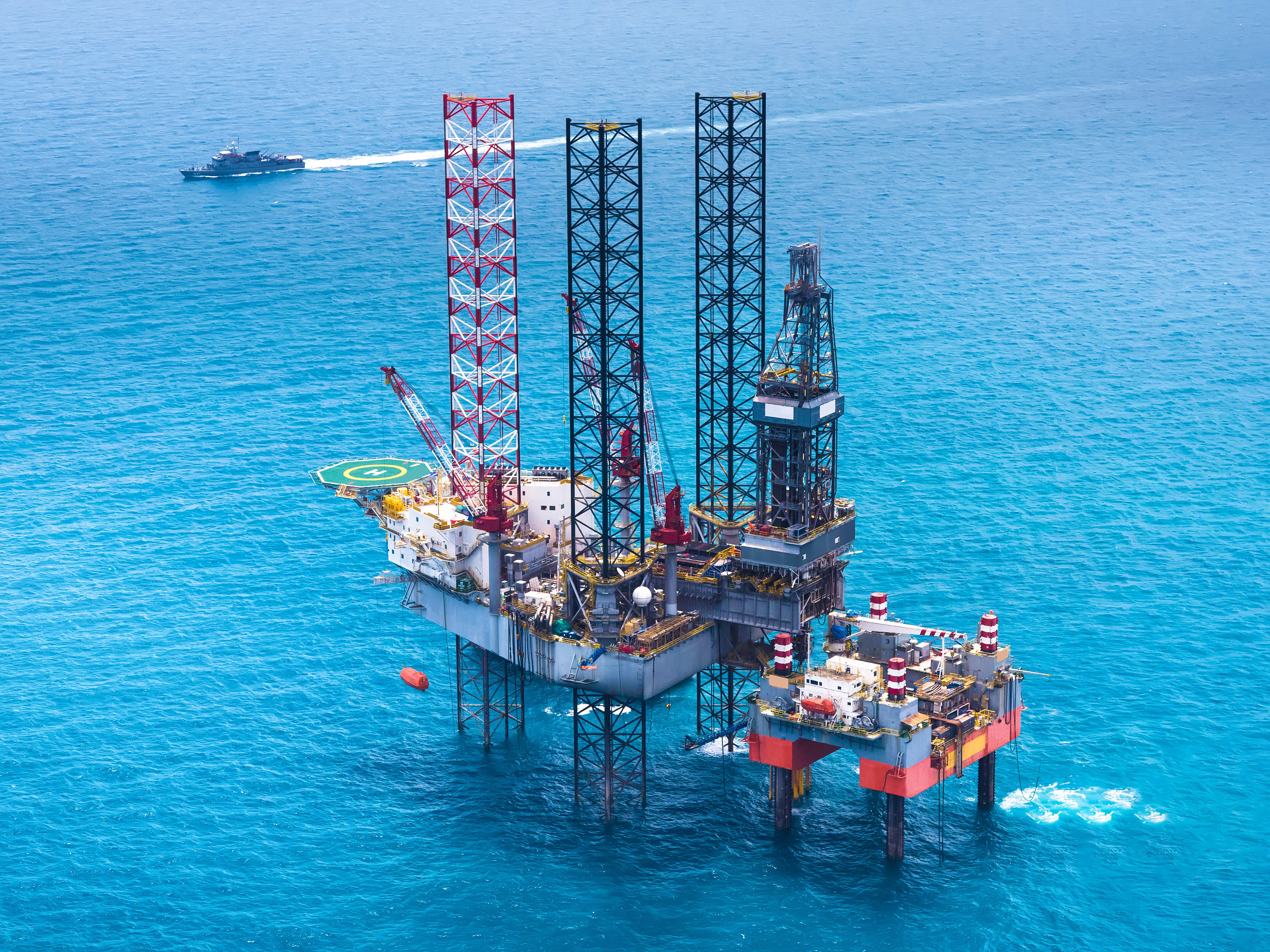 Oil & Gas industry Offshore oil rig from distance on water level with a ship in the background