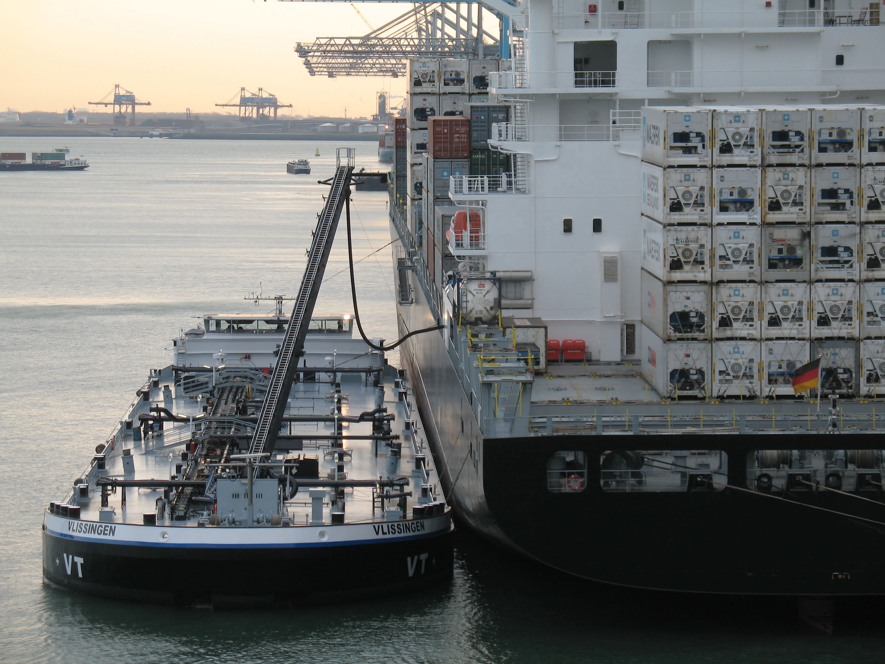 Tanker ship refuels a large container ship inside the harbour Tanker ship refuels a large container ship inside the harbour